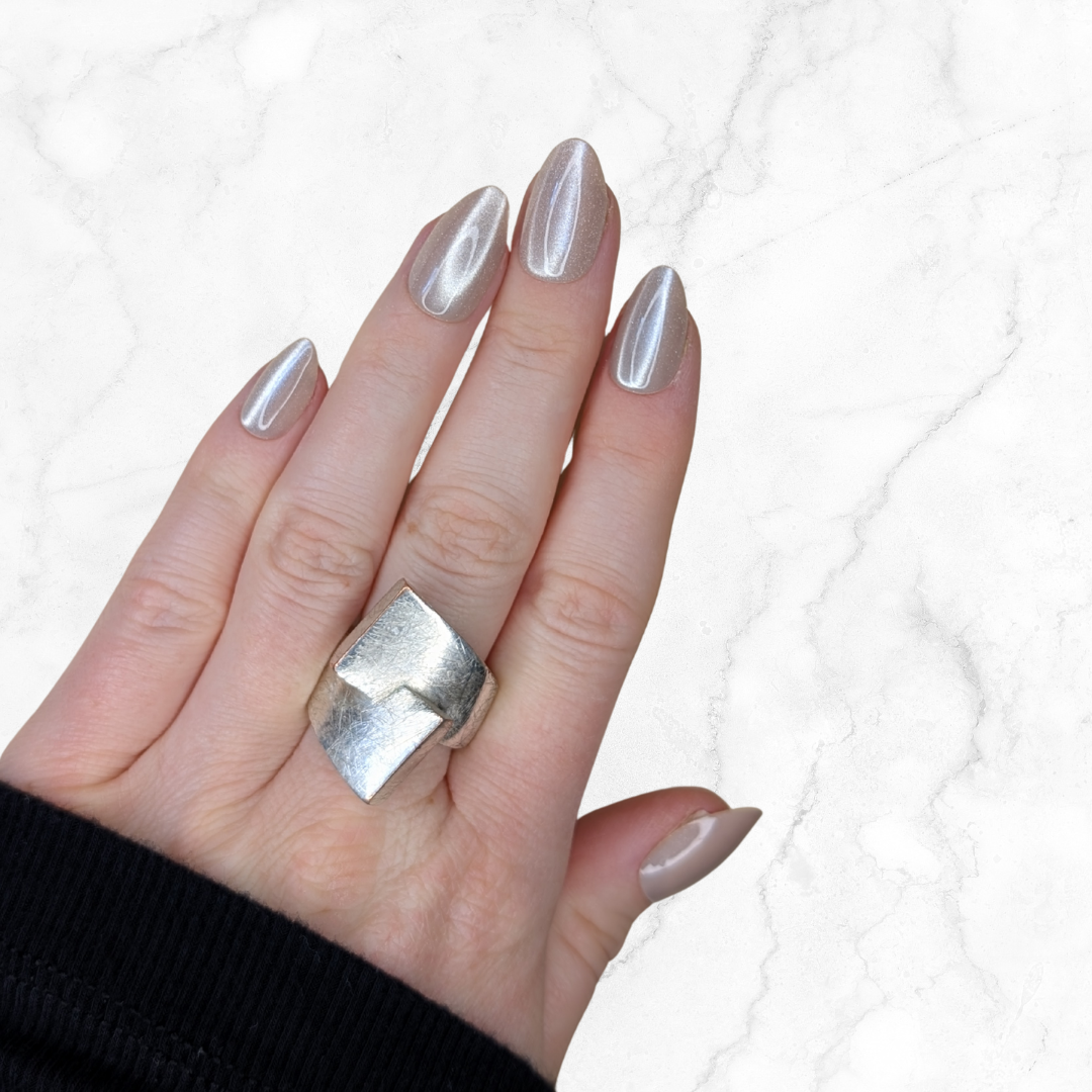 Left hand with almond shaped nails with an latte shiny colour on a marble background.