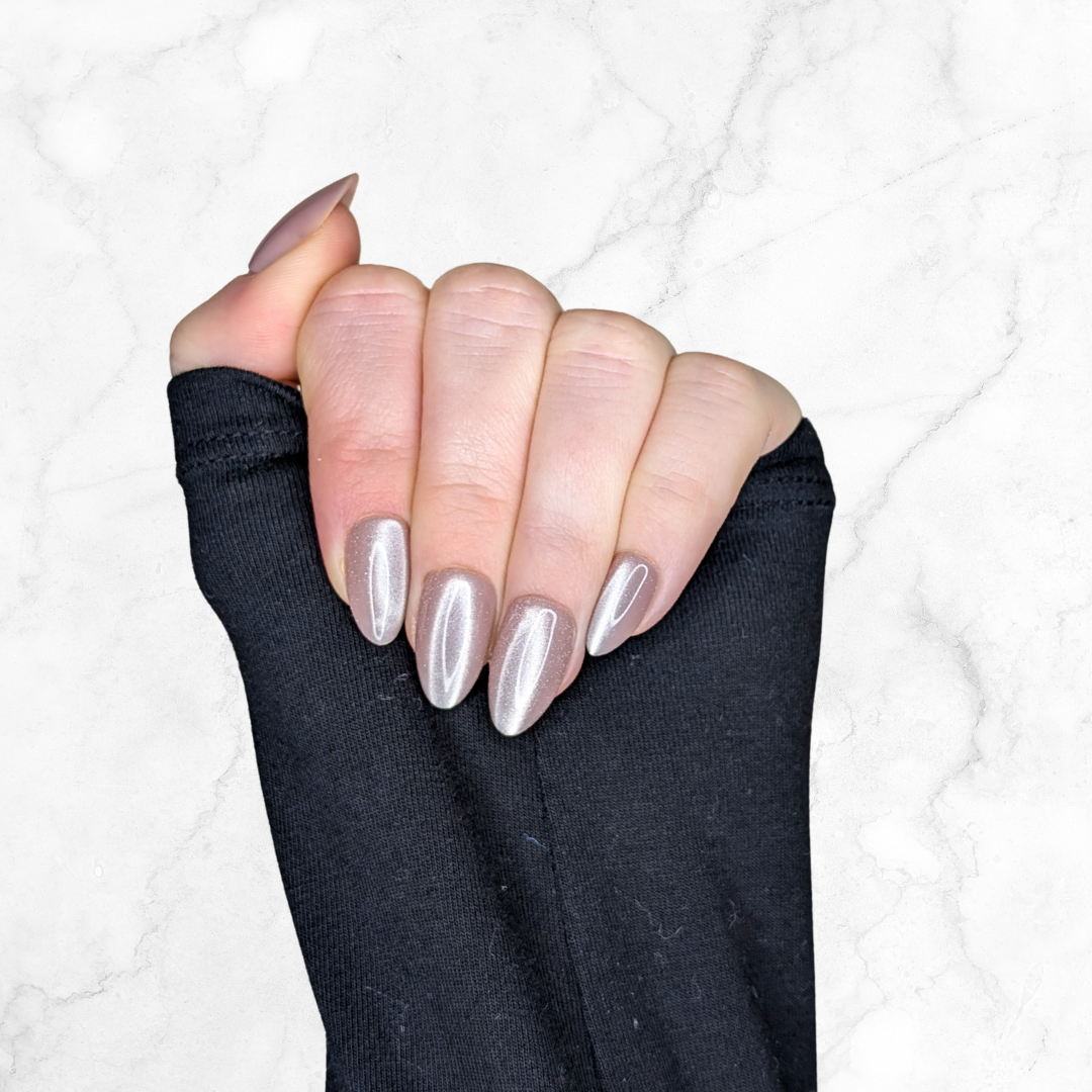 Left hand wearing almond shaped nails in a shiny chocolatey colour on a marble background.