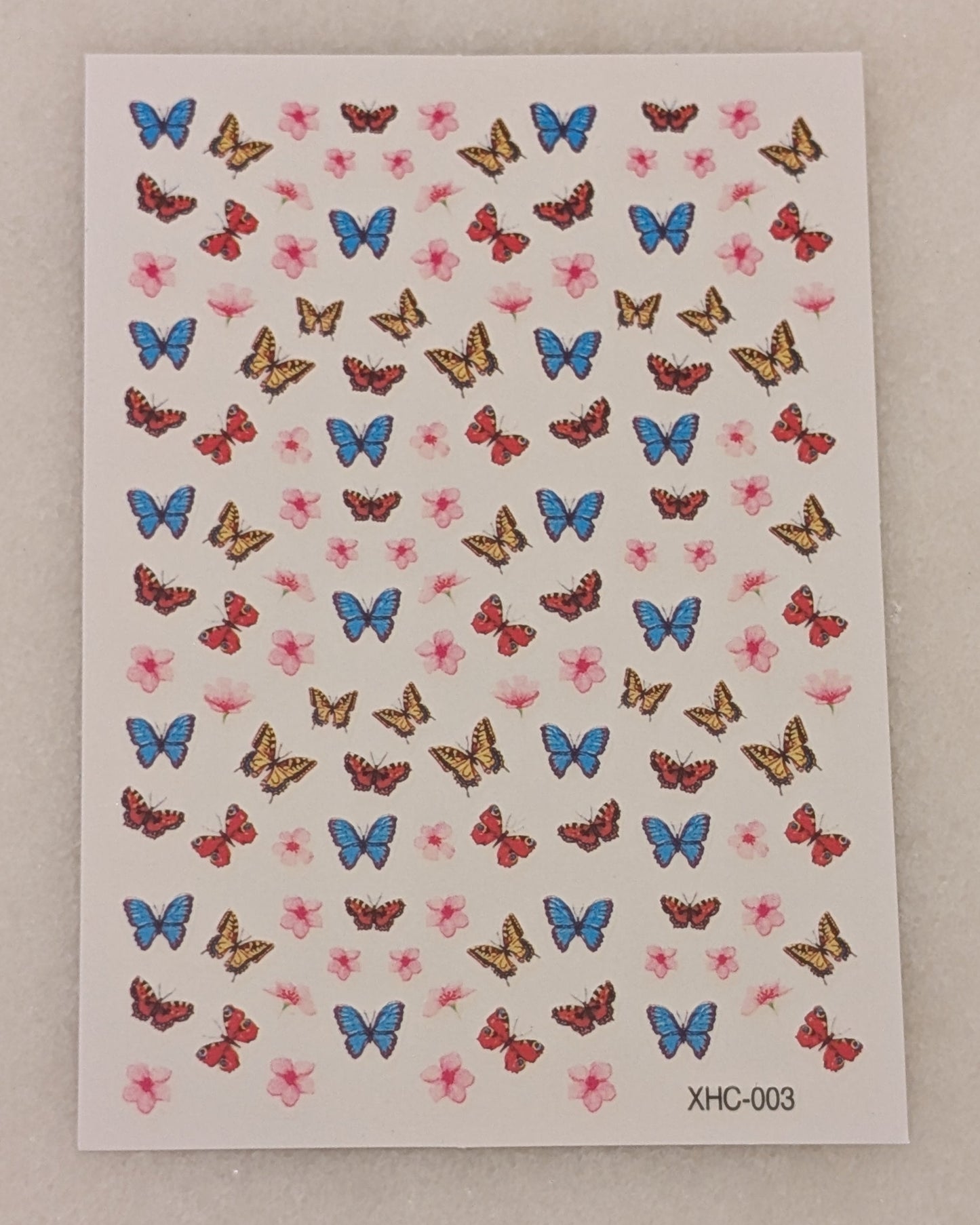 Nail art stickers with blue, yellow and red butterflies as well as pink flowers