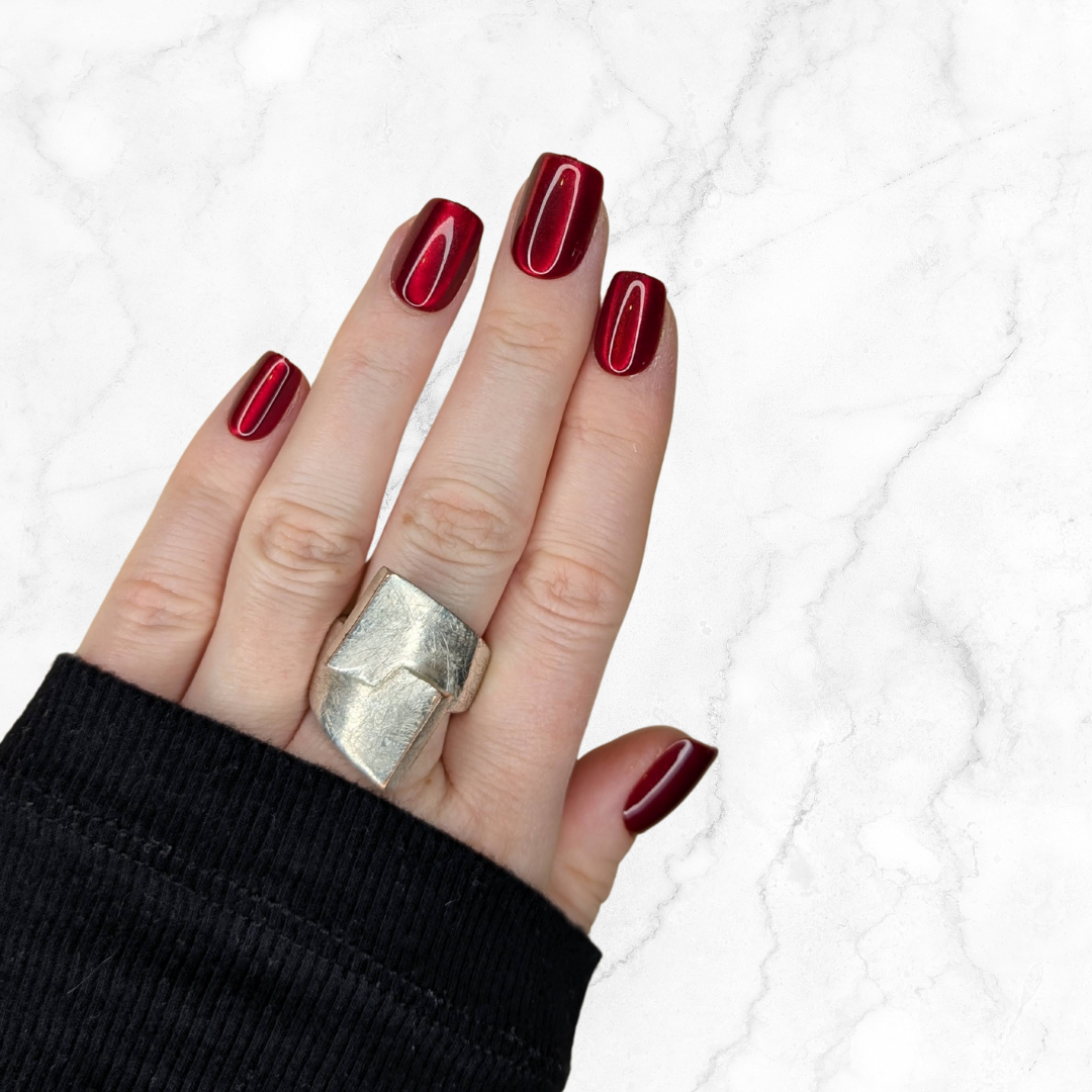 Left hand showing cherry red glaze nails in a square shape on a marble background.
