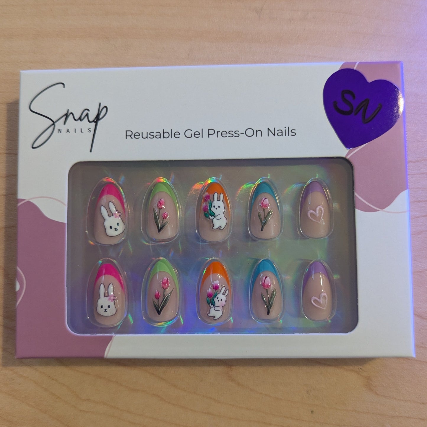 Image of a Snap Nails box with 10 almond press on gel nails with various tip colours and Easter designs.