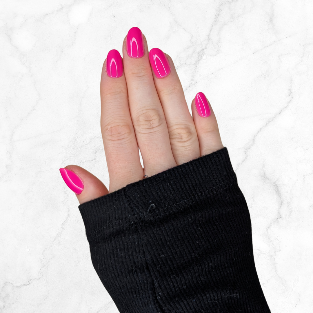 picture of a left hand curled with hot pink oval shaped nails on a marble background.