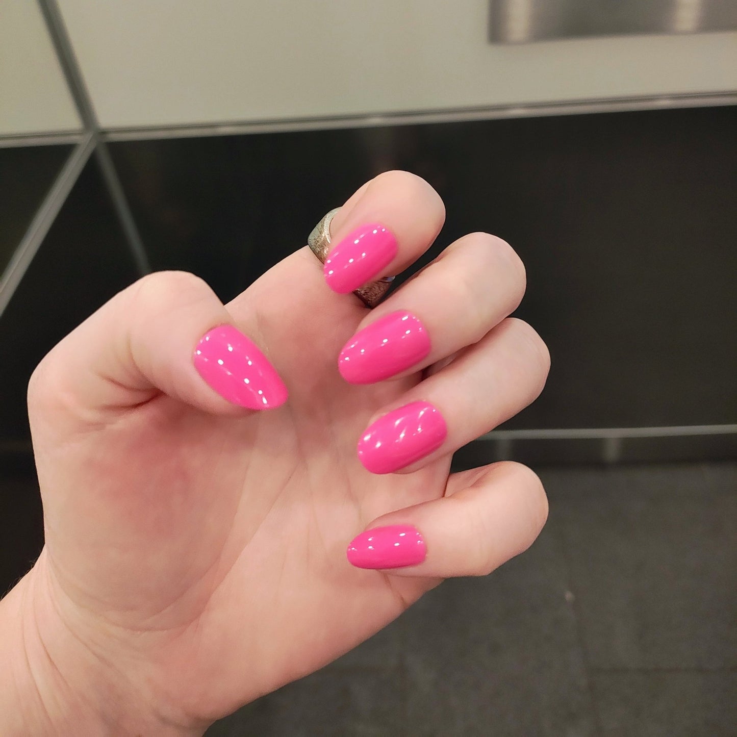 pale left hand with hot pink oval nails, mid length.