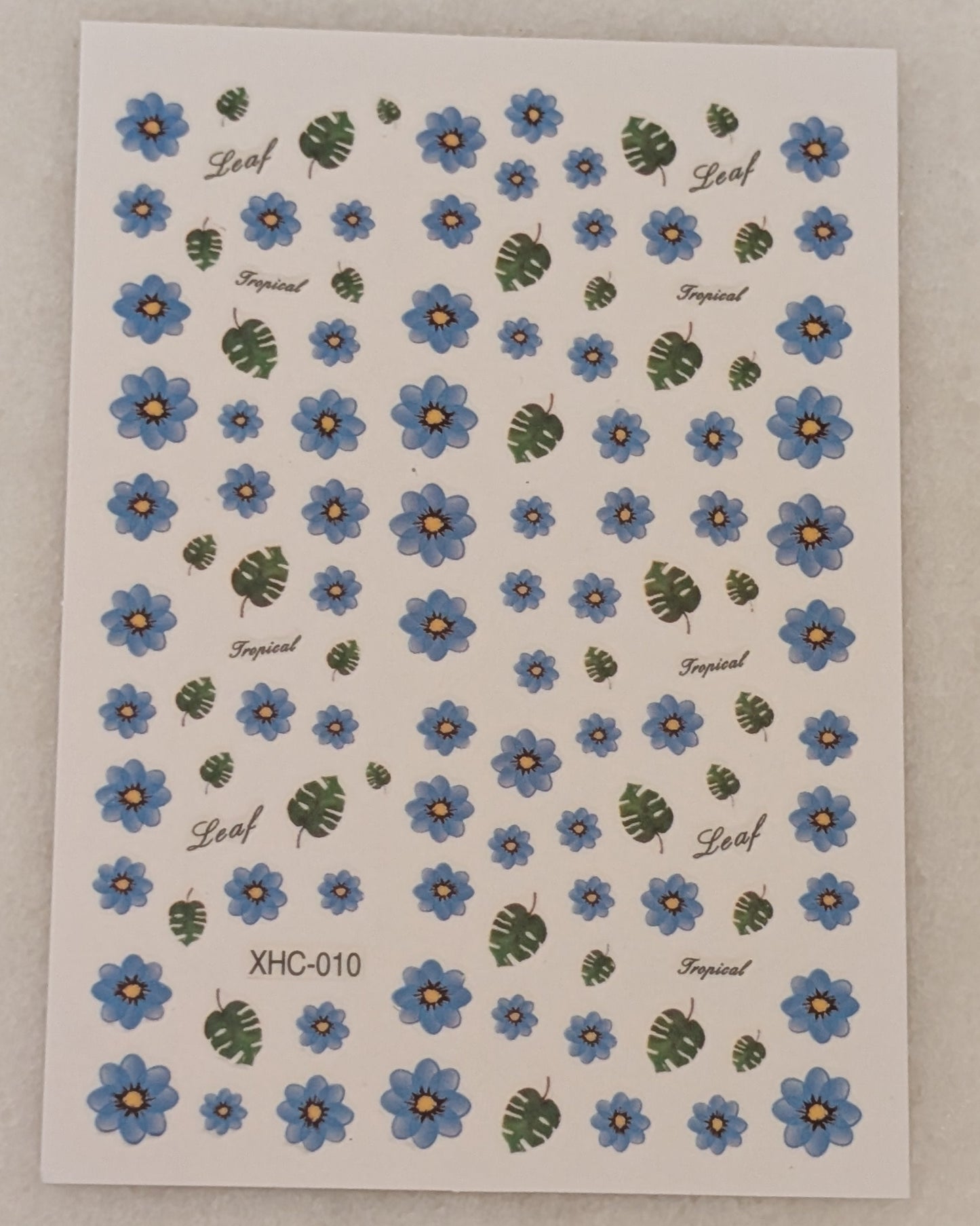 blue flowers of varying sizes along with monstera leaves of varying sizes
