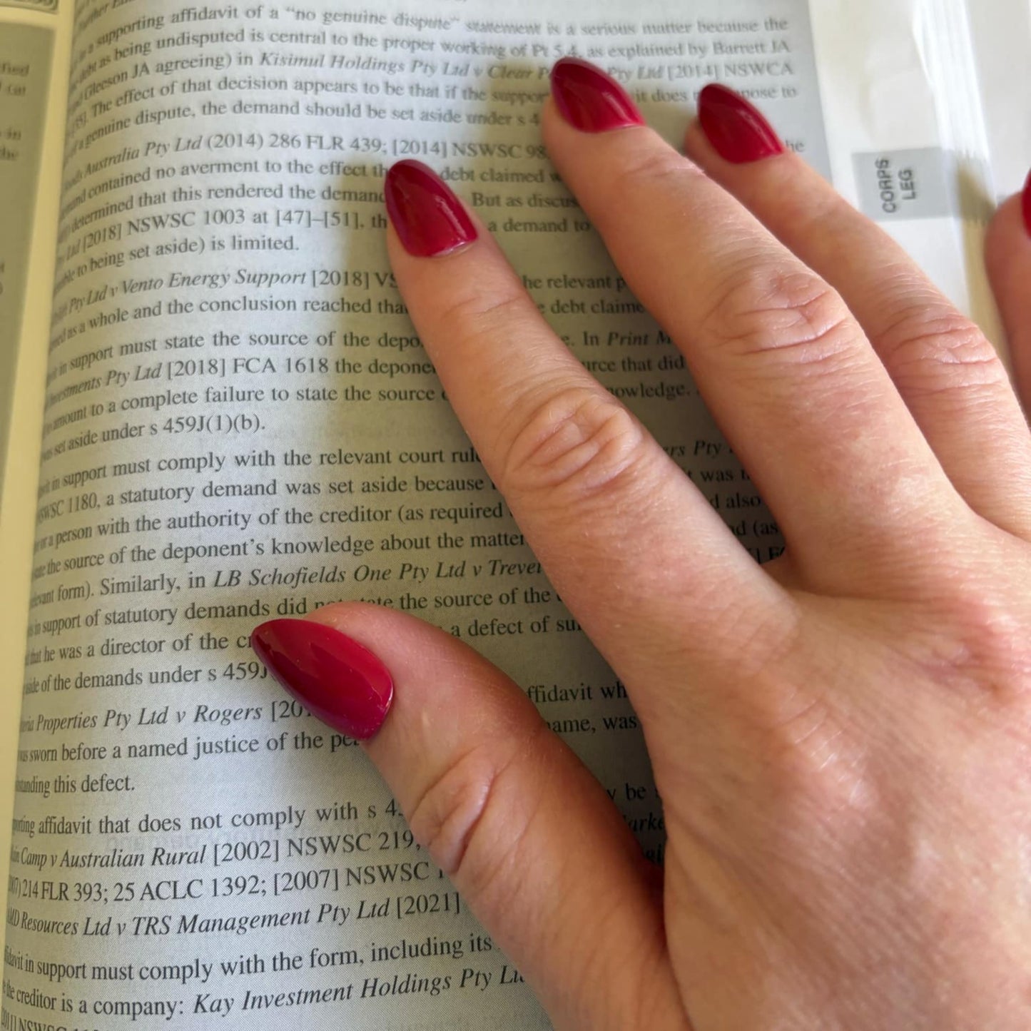 Right hand showing deep red oval shaped sitting on a legal textbook.