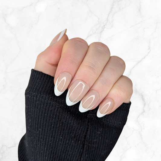 Left hand showing classic almond French tipped nails on a marble background.