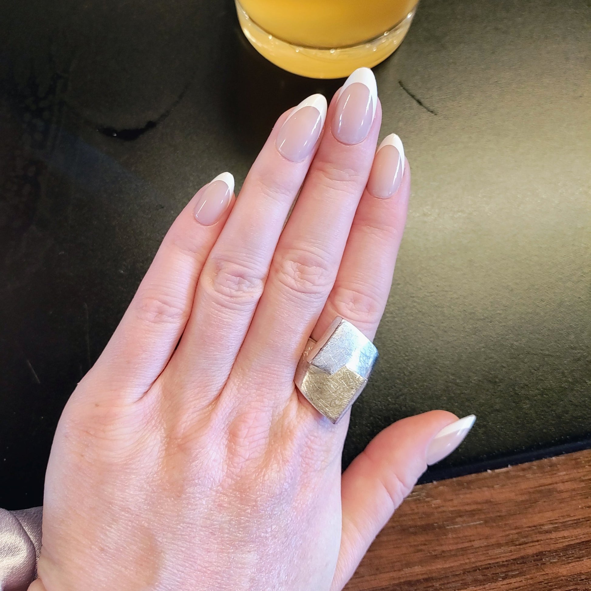 Left nail showing a classic almond French tip next to a pint of beer.