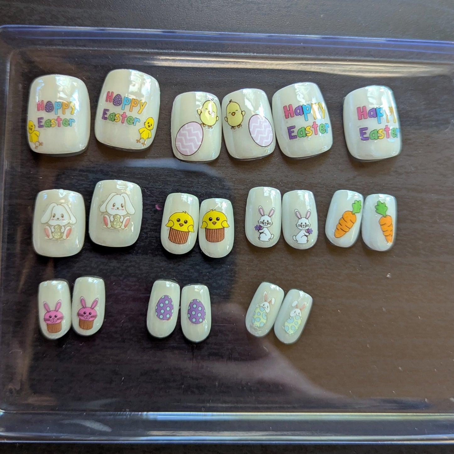 Image of a clear box with 20 square pearl press on gel nails with various Easter designs.