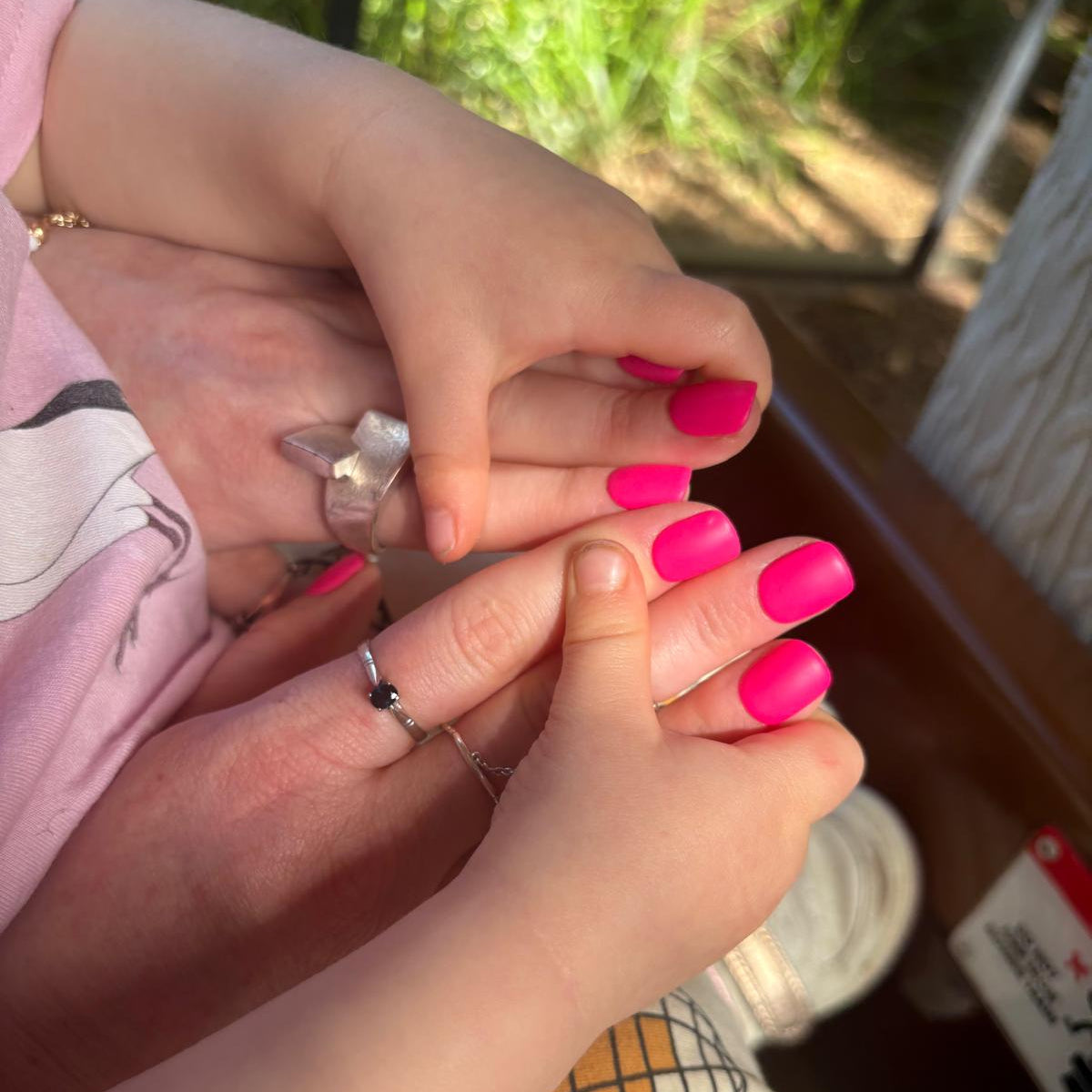 toddler hands holding mothers hand who has hot pink short square nails on.