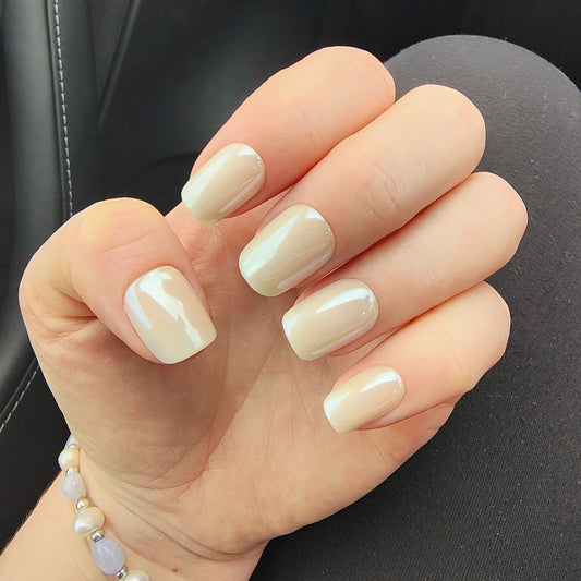 Left hand showing square pearl coloured nails on black leggings.