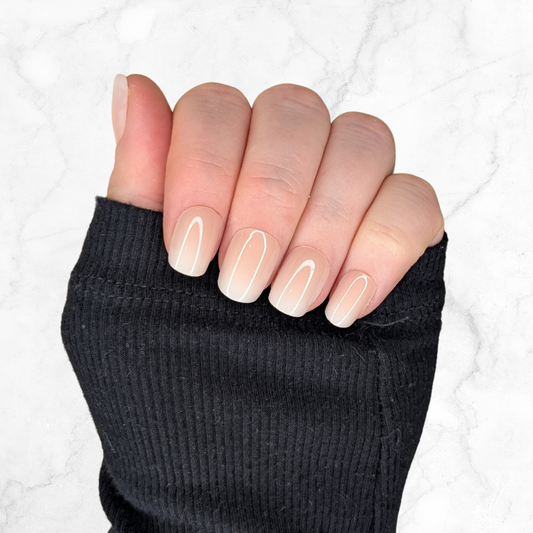 Right hand showing square nails with an ombre effect of peach to white on a marble background.
