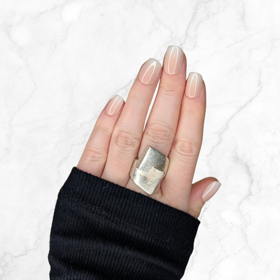 Right hand showing square nails with an ombre effect of peach to white on a marble background.