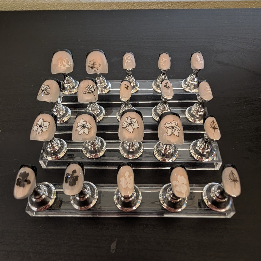 Image of 20 Snap Nails in Signature collection square black french tip nails with black and white fine black and white details on little nail pedestals.