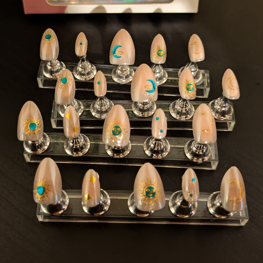 Image of 20 Snap Nails in Signature collection almond star dust nails with gold details on little nail pedestals.