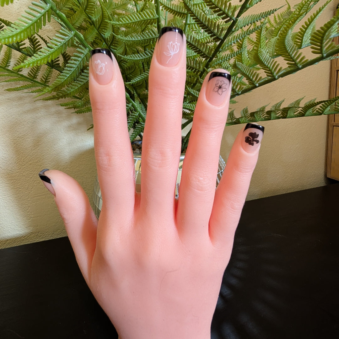 Image of a right hand wearing Snap Nails in Signature collection of 5 square black french tip nails with black and white fine black and white details.