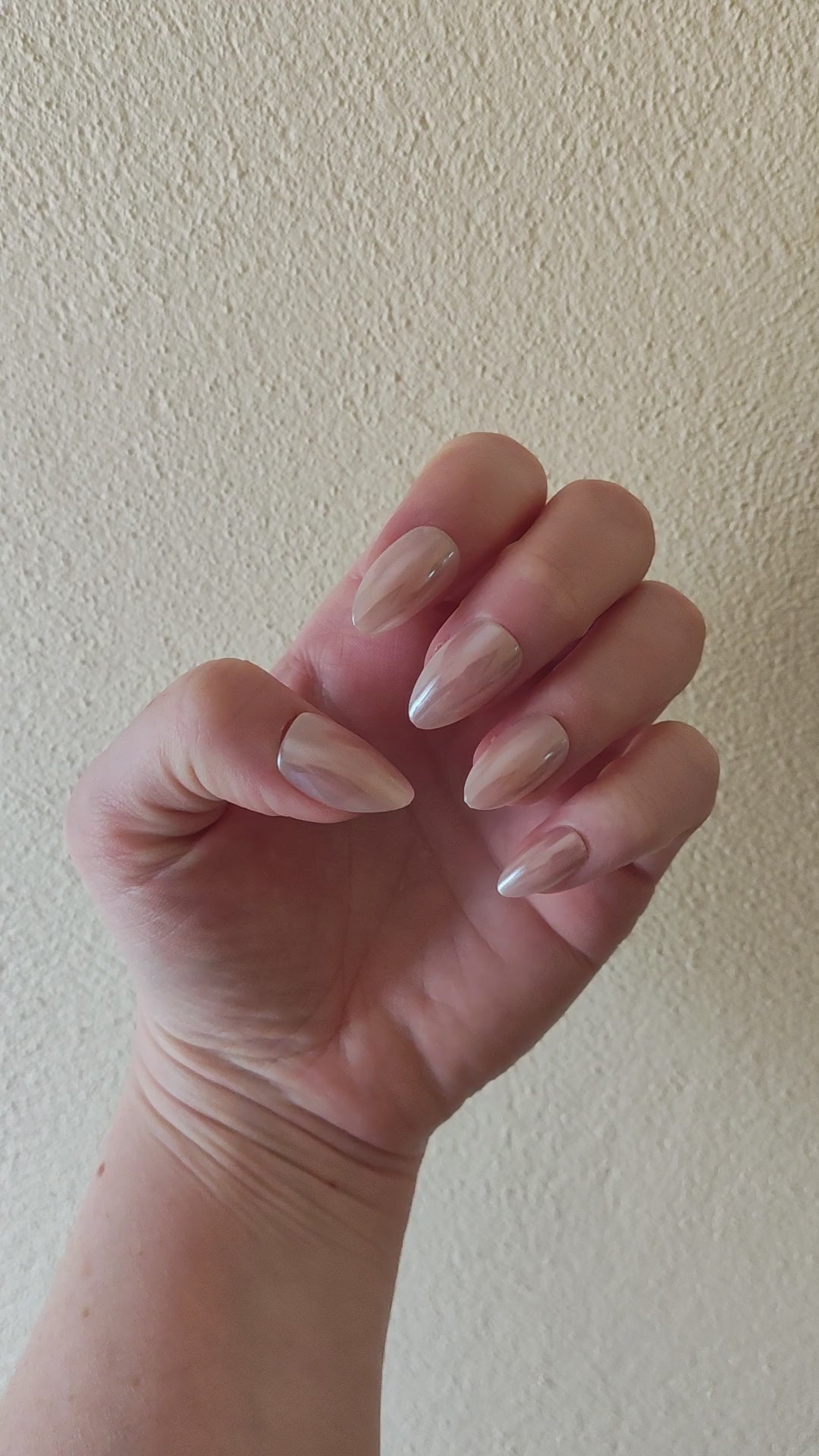 Left hand showing an almond shimmery, pinky peach coloured nails on a faux fur blanket.