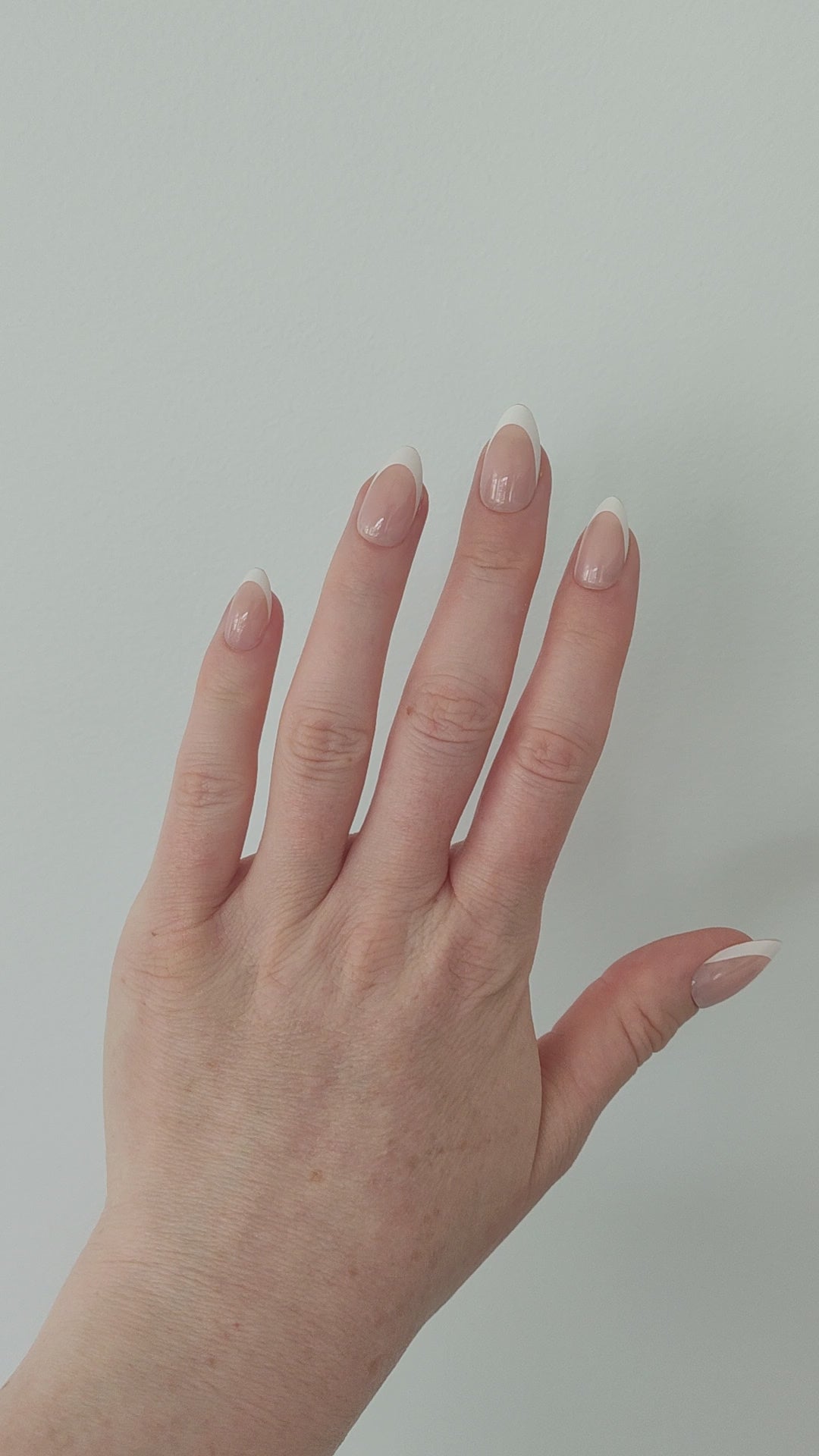 Left nail showing a classic almond French tip on a white background.