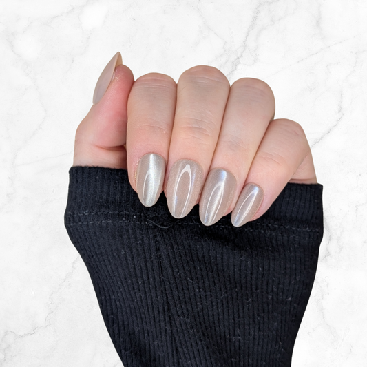 Left hand with almond shaped nails with an latte shiny colour on a marble background.