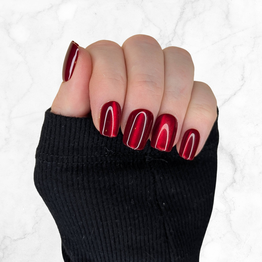 Left hand showing cherry red glaze nails in a square shape on a marble background.