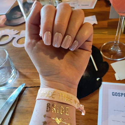 Left hand with square blush pink nails on a table.