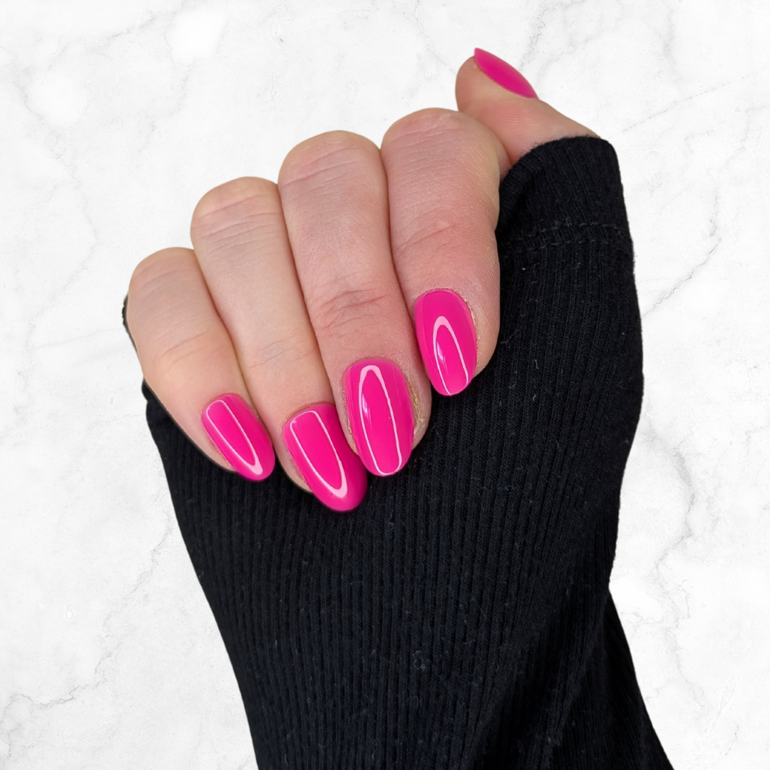 picture of a left hand curled with hot pink oval shaped nails on a marble background.