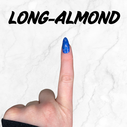 Finger wearing blue and purple marbled press-on nails with silver sparkle in a long almond shape.