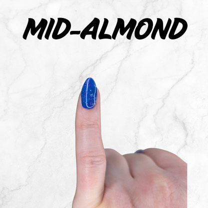 Finger wearing blue and purple marbled press-on nails with silver sparkle in a mid almond shape.
