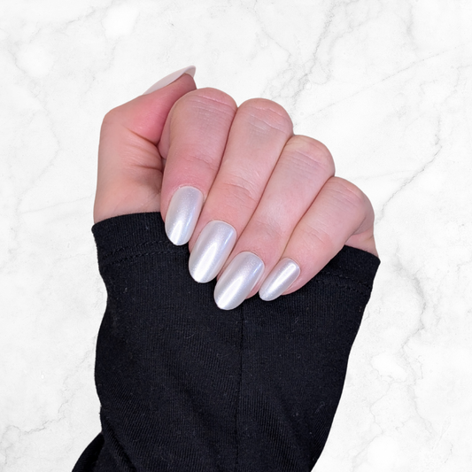 Left hand showing oval pearl coloured nails on a marble background.