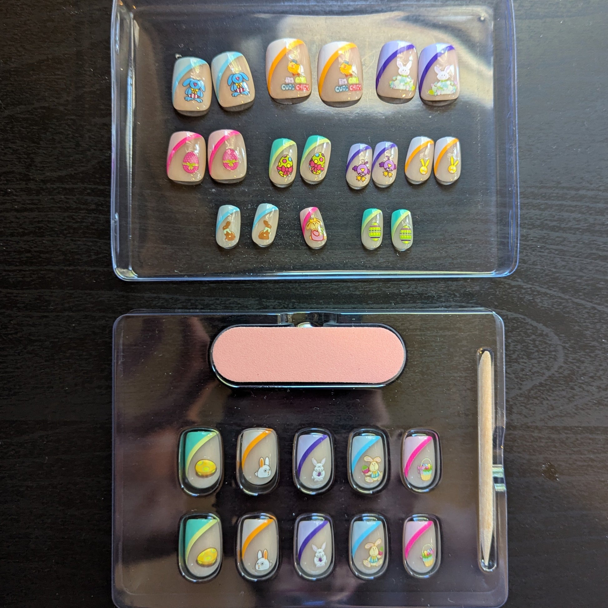 Image of a clear box with square gel press-ons with 19 nails of varying tip colours and Easter designs. Underneath is another clear box with 10 square press on gel nails with various tip colours and Easter designs, a cuticle stick and a nail file.