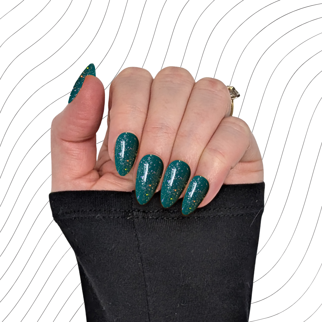 Left hand showing emerald green short almond nails with a glitter gloss finish on a wavy background.