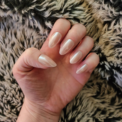 Left hand showing an almond shimmery, pinky peach coloured nails on a faux fur blanket.