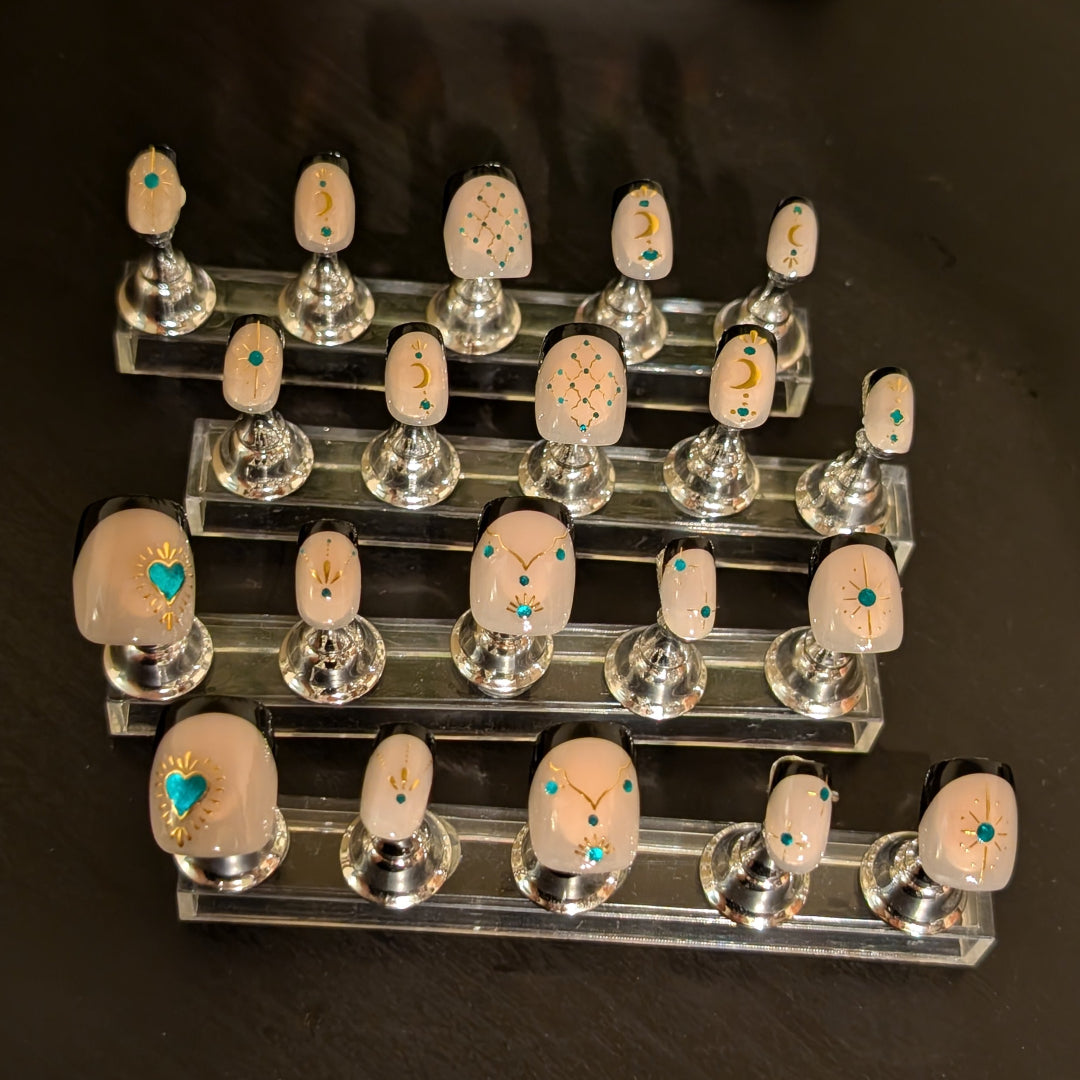 Image of 20 Snap Nails in Signature collection square black french tip nails with gold details on little nail pedestals.