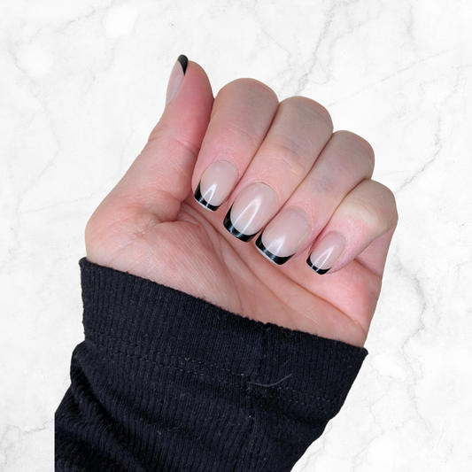 Left hand showing black French tipped squared nails on a marble back ground.