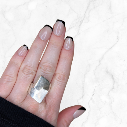 Left hand showing black French tipped squared nails on a marble back ground