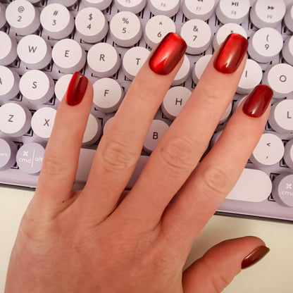 Hand  on top of purple keyboard showing deep cherry red square nails