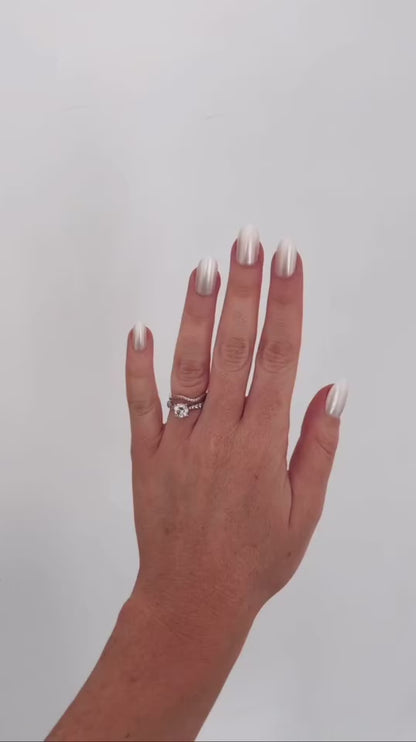 Left hand showing oval pearl coloured nails on a white wall.