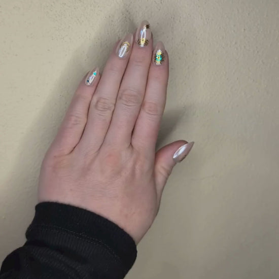 Video of a left hand wearing Snap Nails in Signature collection of 5 almond shimmery, peachy nails gold details