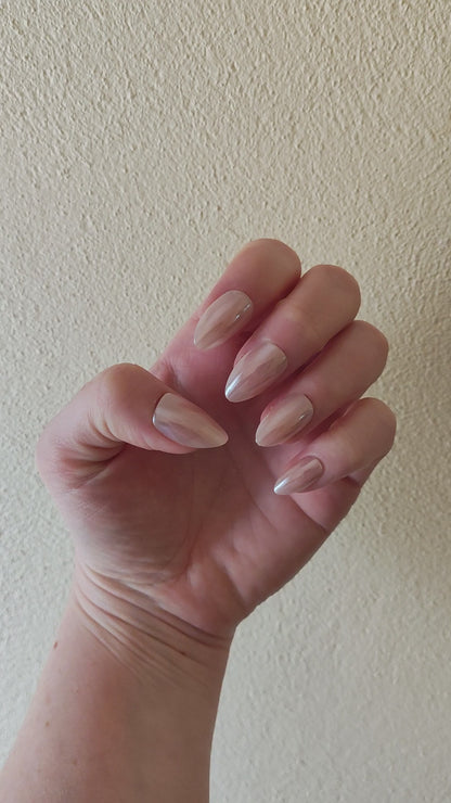 Left hand showing an almond shimmery, pinky peach coloured nails on a faux fur blanket.