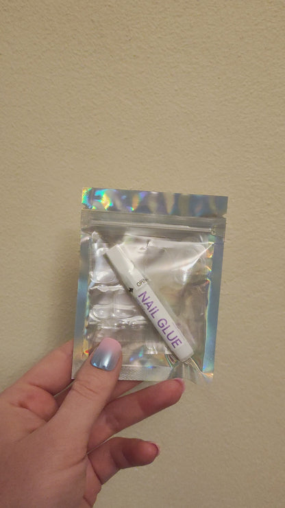 Left hand showing a silver holographic small bag with a Snap Nails logo and small glue and nail gel stickers.